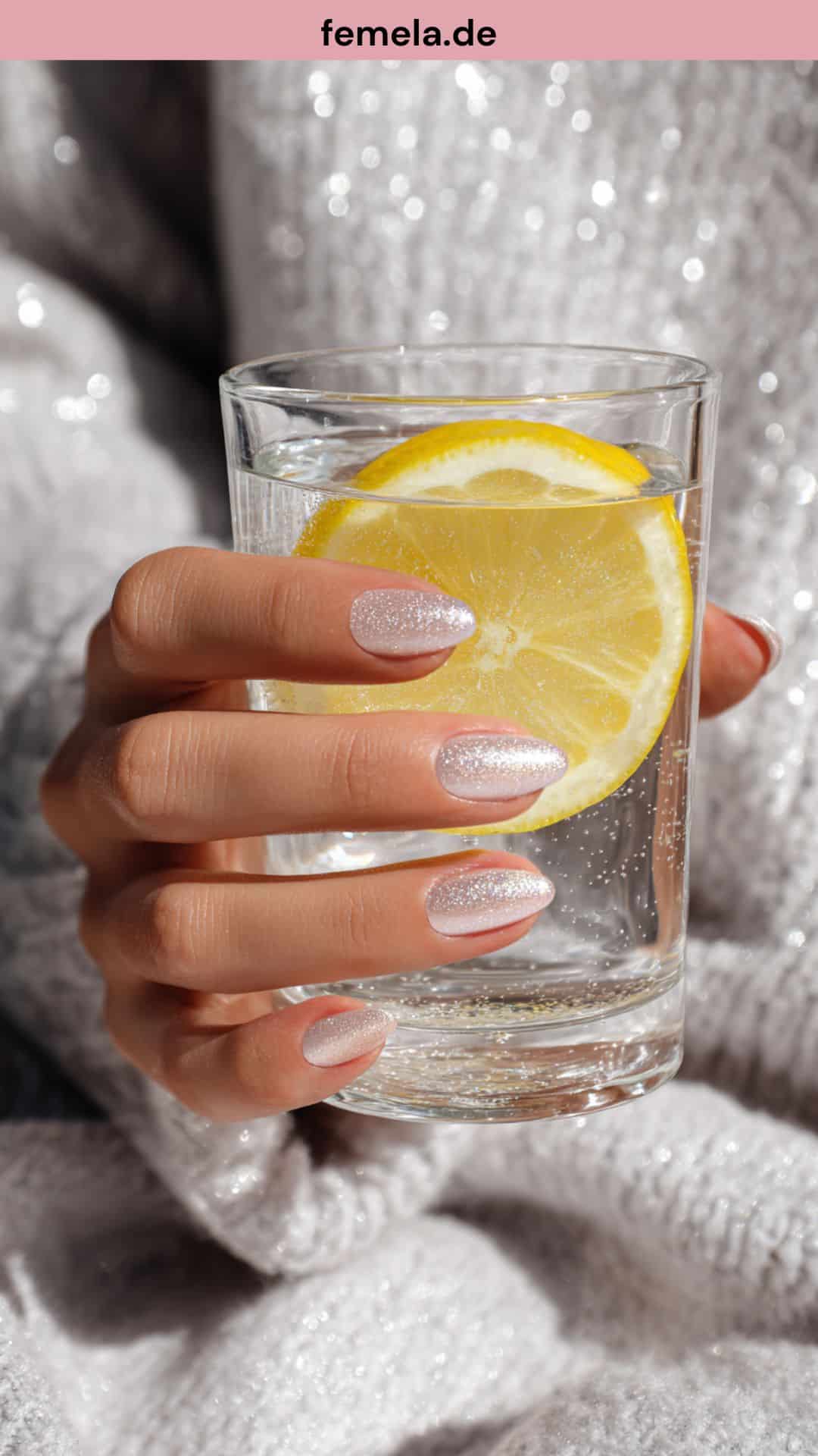 Glamouröse Hand mit Glazed Donut Nägeln hält Wasserglas.