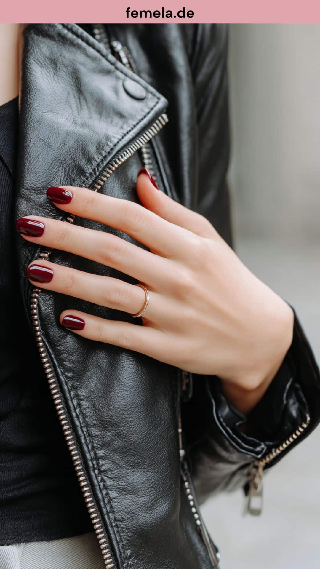 Kurze Nägel in Rouge Noir an einer Lederjacke.