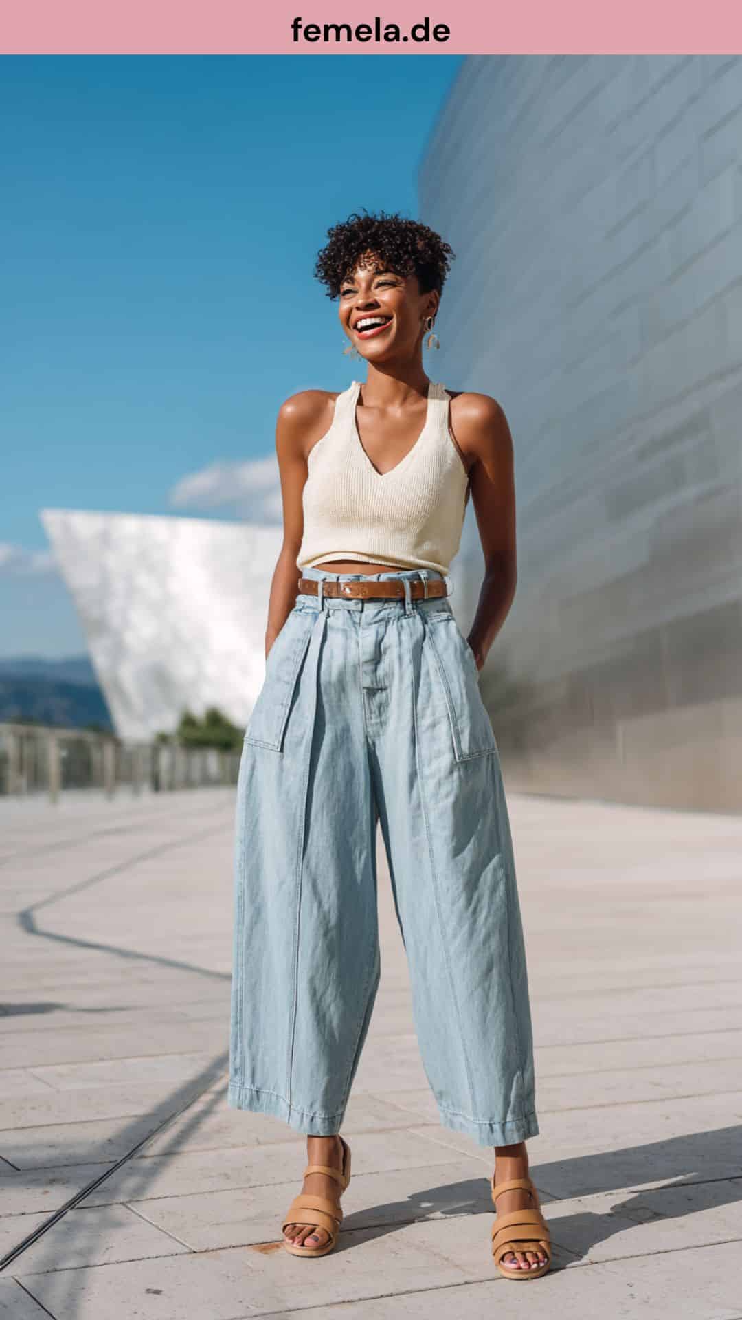 Frau trägt eine weite Wide Leg Jeans mit einem cremefarbenen Crop Top in einer modernen Stadtumgebung.