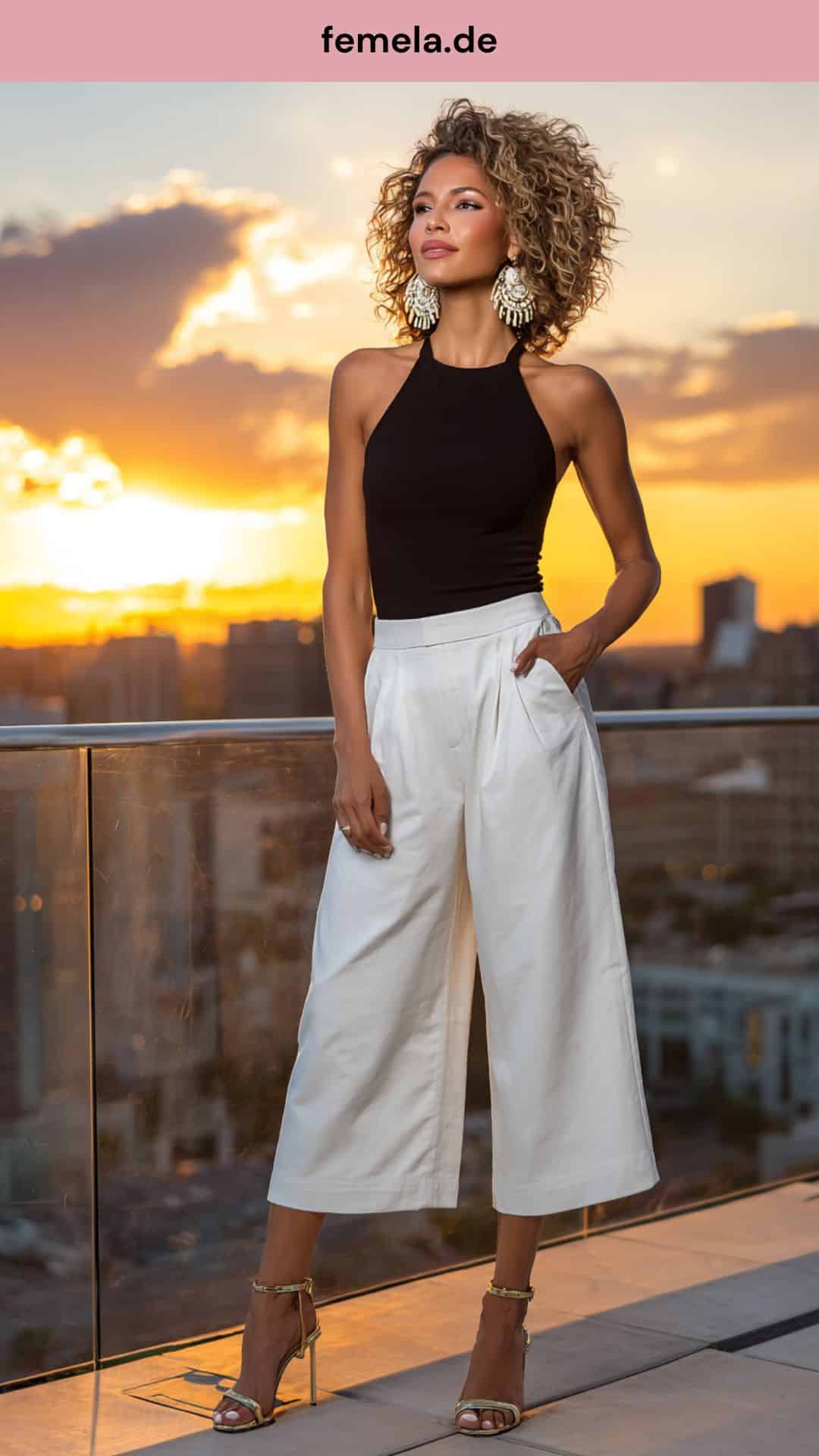 Elegantes Abend-Outfit mit weiter weißer Jeans und schwarzem Top bei Sonnenuntergang.