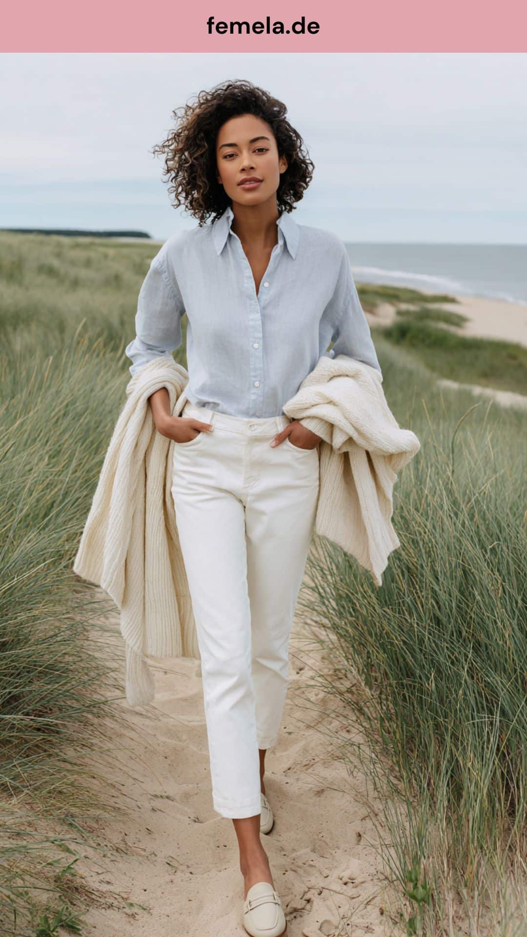 Edler Coastal Grandmother Look mit hellblauem Hemd und weißer Jeans am Strand.