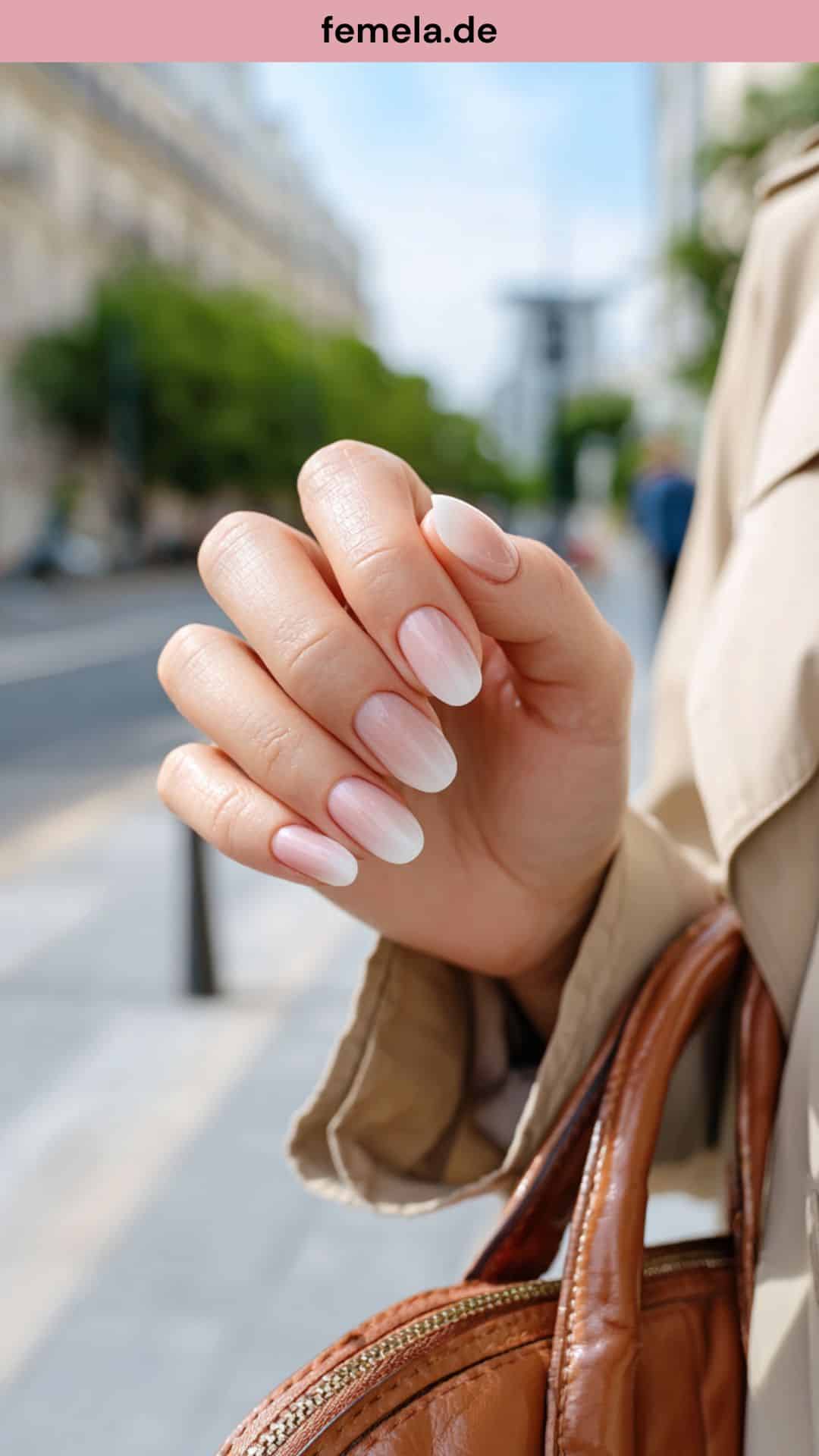 Hände mit eleganten Babyboomer-Nägeln halten eine Handtasche