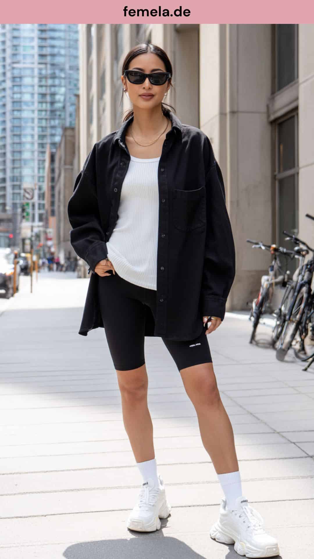 Urbanes Outfit mit offener schwarzer Oversize-Bluse, weißem Top und Radlerhose.